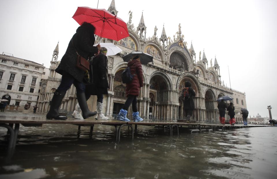 People walk on catwalk set up in front of St. Mark's Basilica on the occasion of a high tide, in a flooded Venice, Italy, Tuesday, Nov. 12, 2019. (Photo: Luca Bruno/AP)