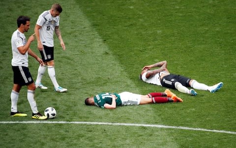 Germany's Jerome Boateng and Mexico's Javier Hernandez lay on the pitch as Mats Hummels and Toni Kroos walk  - Credit: Reuters