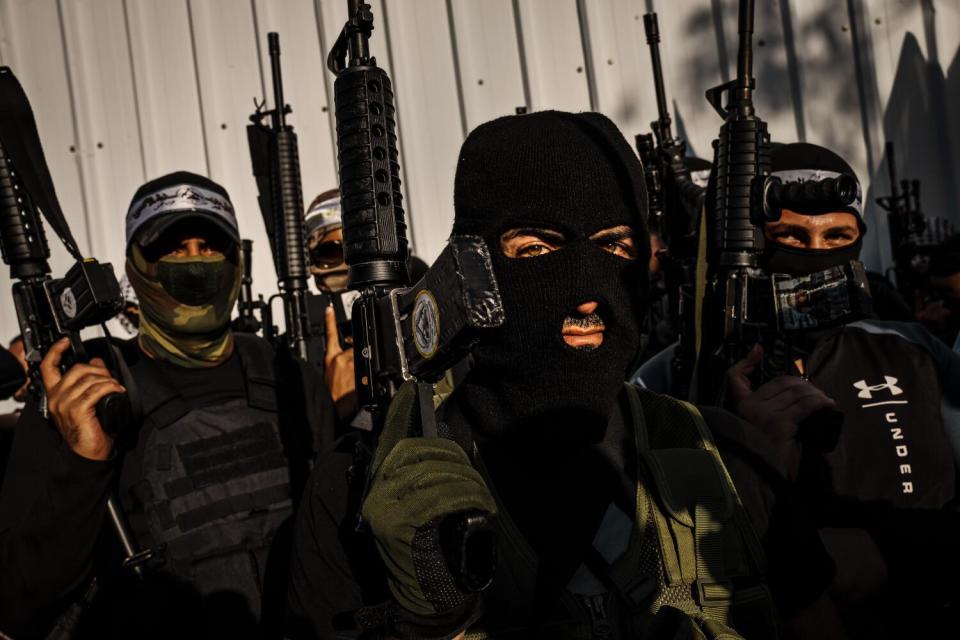 Men hold automatic weapons, their faces hidden behind masks.