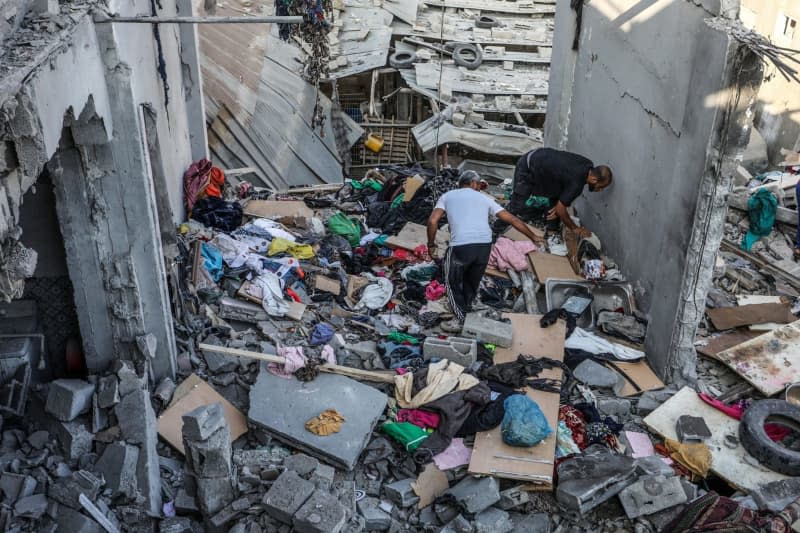 Palestinians search the ruins of a destroyed family house after it was hit by an Israeli air strike on the Nuseirat refugee camp. Abed Rahim Khatib/dpa