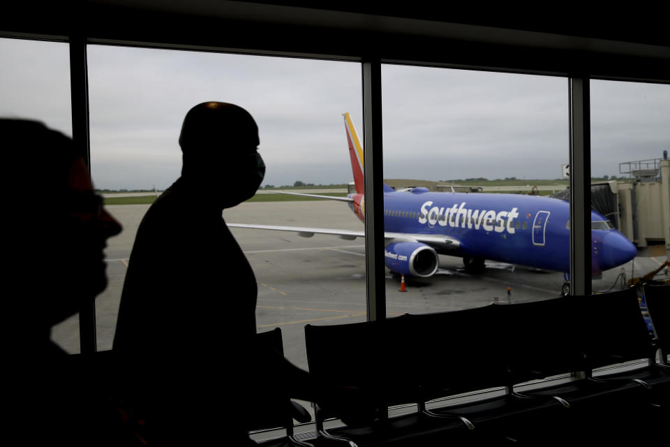 FILE - In this Sunday, May 24, 2020, file photo, people walk to a gate to board a Southwest Airlines flight to Orlando, Fla., at Kansas City International airport in Kansas City, Mo. Congress’ $900 billion pandemic relief package, which passed Monday, Dec. 21, 2020, includes $15 billion for the airline industry and an extension of their Payroll Support Program from the previous rescue bill in March. (AP Photo/Charlie Riedel, File)