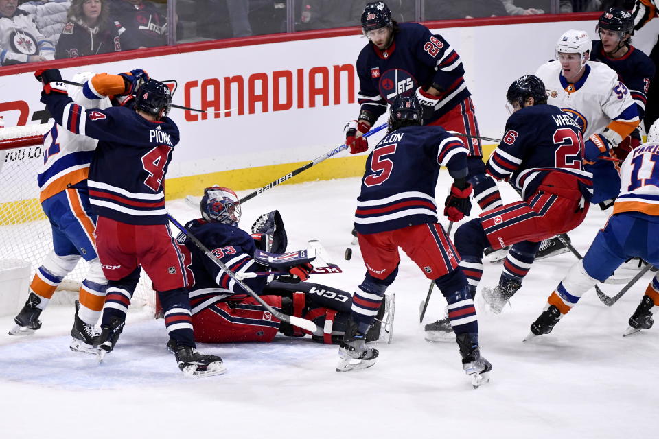 Winnipeg Jets goaltender David Rittich (33) makes a save against a shot by the New York Islanders as players crowd around for the rebound during first-period NHL hockey game action in Winnipeg, Manitoba, Sunday, Feb. 26, 2023. (Fred Greenslade/The Canadian Press via AP)