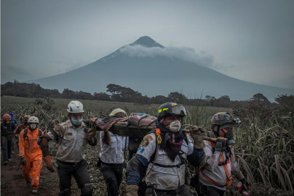 Rescuers carry a body in San Miguel Los Lotes on June 4. In the background is the Volcán de Agua, which has no history of eruptions.