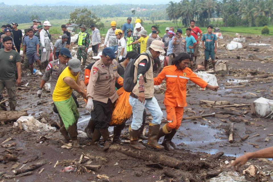 Rescuers carry the body of a victim of a flash flood in Tanah Datar, West Sumatra, Indonesia (AP)