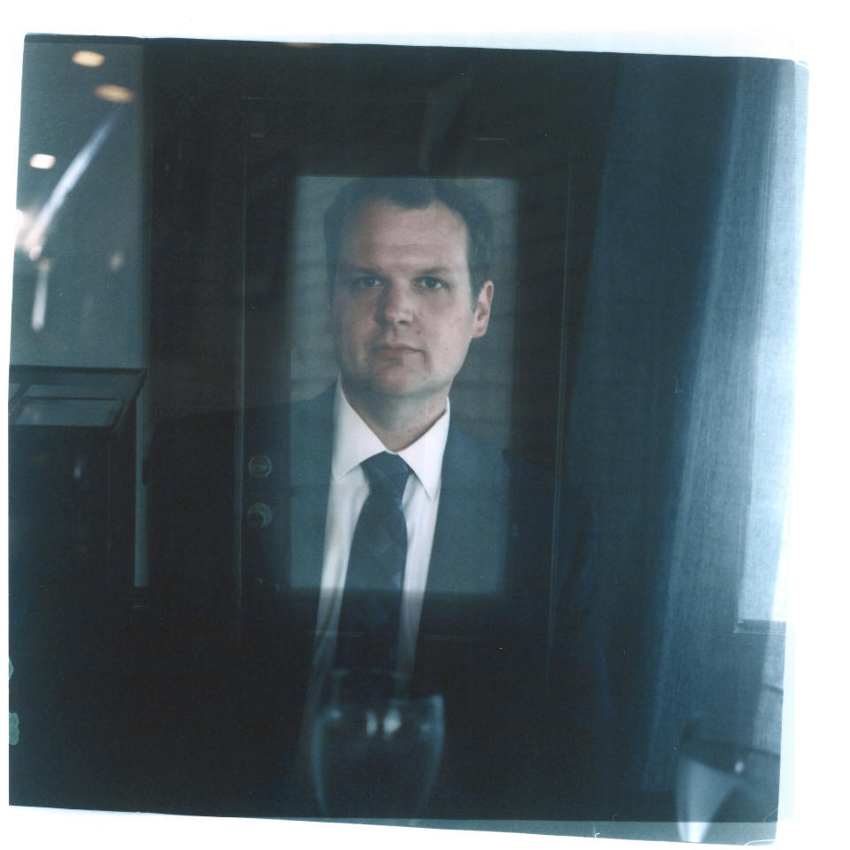 In this double exposure darkroom print made from two film negatives, a portrait of Hollan Holm seated in a restaurant is layered with a photo of the front door he's facing while out to dinner with his family in Louisville, Ky., Saturday, June 3, 2023. Holm was shot but survived one of the first school mass shootings to shatter the American consciousness a generation ago. Whether or not he wanted to acknowledge the trauma that stemmed from the shooting, though, it remained present. In restaurants, Hollan made sure to get a chair facing the door, intent on watching for approaching threats. When an unfamiliar man wearing a trench coat and carrying a backpack entered church one Sunday, Hollan tensed up, so alarmed by what the visitor might do that he and his wife had to leave. In a country that has weathered a record number of mass killings this year and a surge in youth deaths by firearms, trying to reassure children about the shootings that have become all too common in American life could challenge any parent. It can be even harder for the children of Columbine and a series of school shootings that foreshadowed it, now that they have children of their own. "I mean, I can't really go into crowds of people and not be concerned about maybe somebody's going to do something with a gun … and I don't want them to have to live like that," Holm says of his children. "I just want them to be kids." (AP Photo/David Goldman)