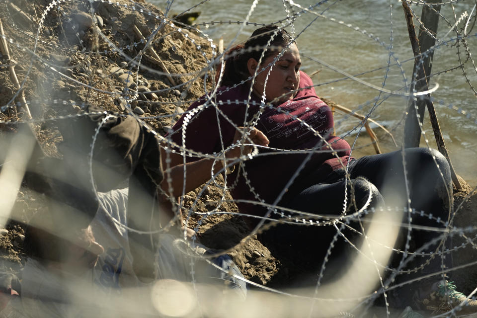 Migrants who crossed the Rio Grande from Mexico to the U.S. work their way through concertina wire, Friday, Sept. 22, 2023, in Eagle Pass, Texas. (AP Photo/Eric Gay)