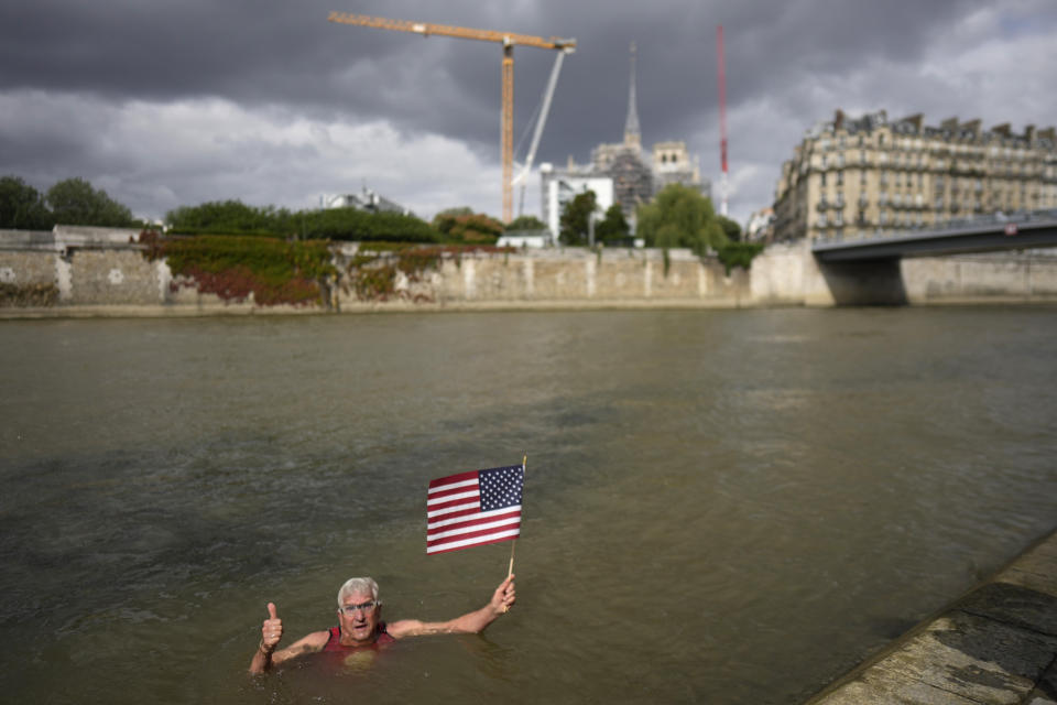 Joel Stratte-McClure, 75, of the US, holds American flag after completing a short swim in the Seine river, Thursday, July 4, 2024 in Paris. The Seine River has been found unsafe according to test results published last Friday, less than a month before the Paris Olympics. (AP Photo/Thibault Camus)