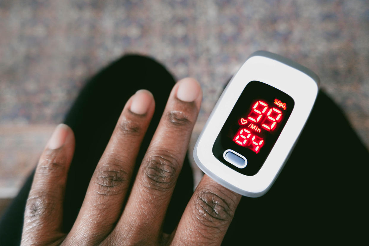 A pulse oximeter gives a reading of 99% blood oxygen saturation level and a heart rate of 84 beats per minute for a Black patient.