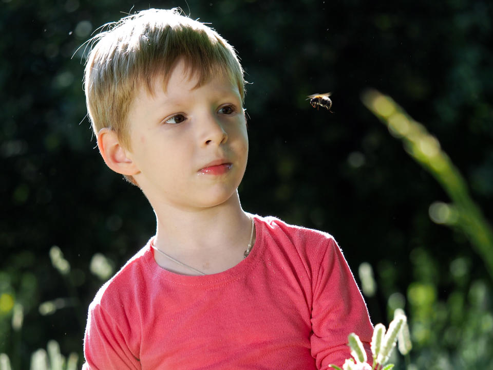 Closeup of a boy looking at a bee that's flying toward him