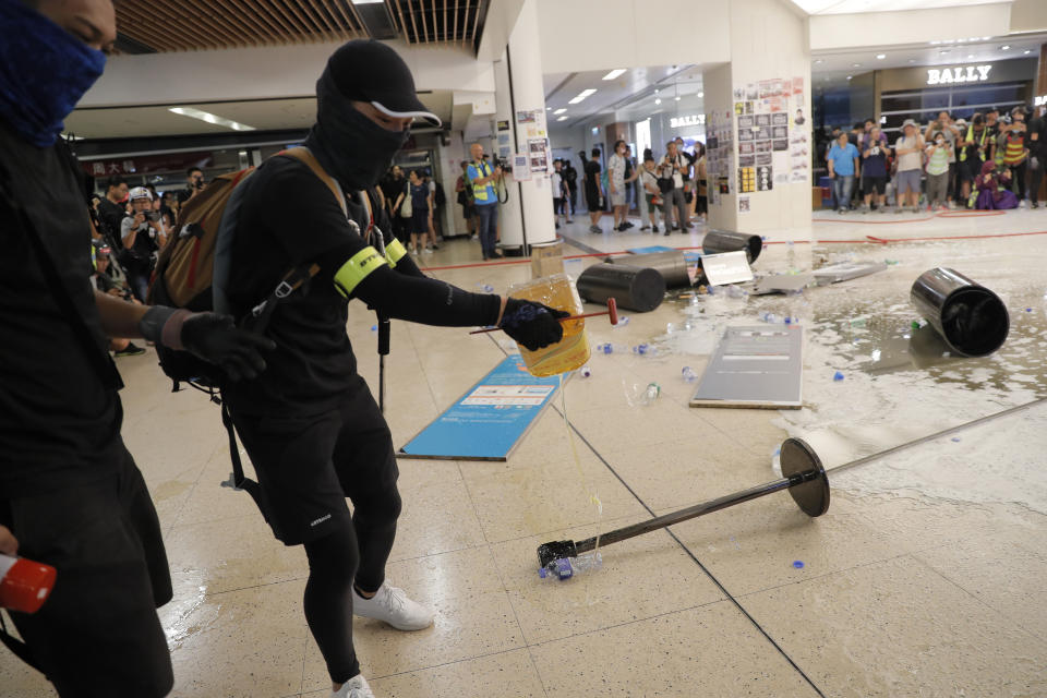 Protesters pour cooking oil onto the floor near a subway station in Hong Kong on Sunday, Sept. 22, 2019. Protesters smashed surveillance cameras and electronic ticket sensors in the subway station, as pro-democracy demonstrations took a violent turn once again. (AP Photo/Kin Cheung)