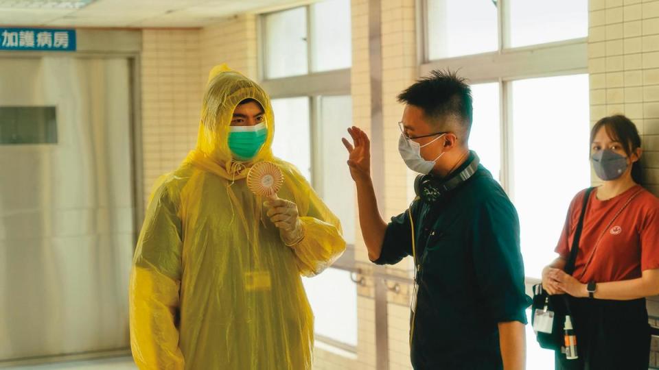 飾演醫師的王柏傑（左）穿防護衣全身飆汗，邊吹電扇、邊和導演林君陽（中）討論。（CatchPlay提供）