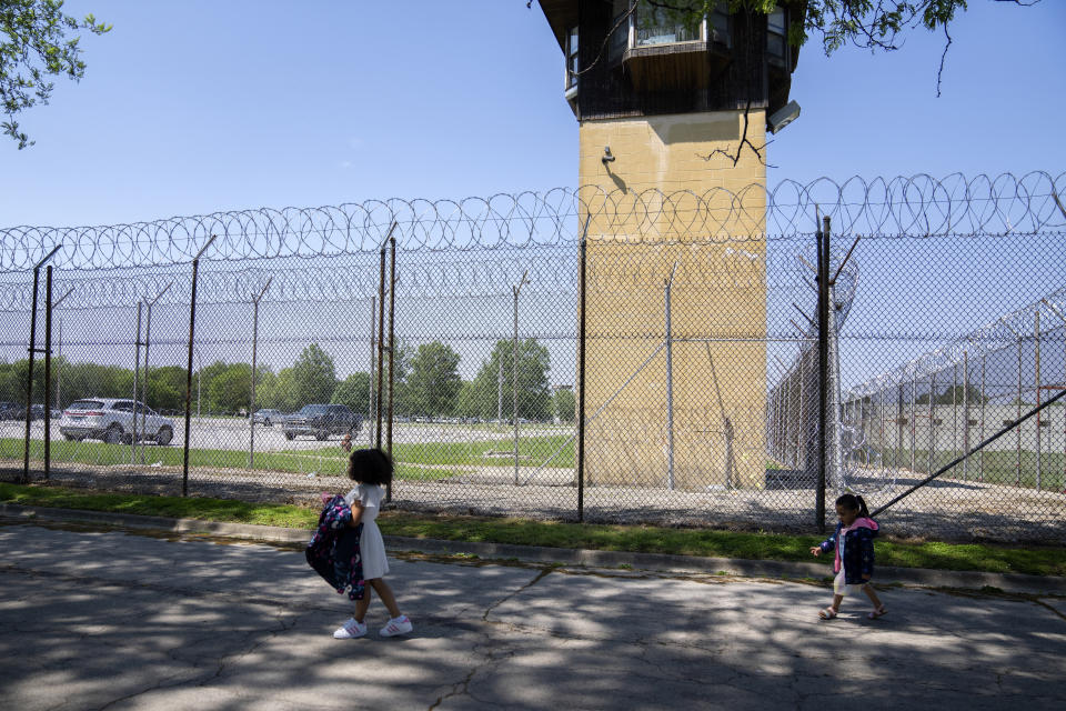 Myla Martinez, 6, left, and her sister Jaliyah Santiago, 4, pass by a guard tower as they leave Logan Correctional Center after visiting their mother Crystal Martinez, Saturday, May 20, 2023, in Lincoln, Illinois. Rare programs like the Reunification Ride, a donation-dependent initiative that buses prisoners' family members from Chicago to Illinois' largest women's prison every month so they can spend time with their mothers and grandmothers, are a crucial lifeline for families, prisoners say. (AP Photo/Erin Hooley)