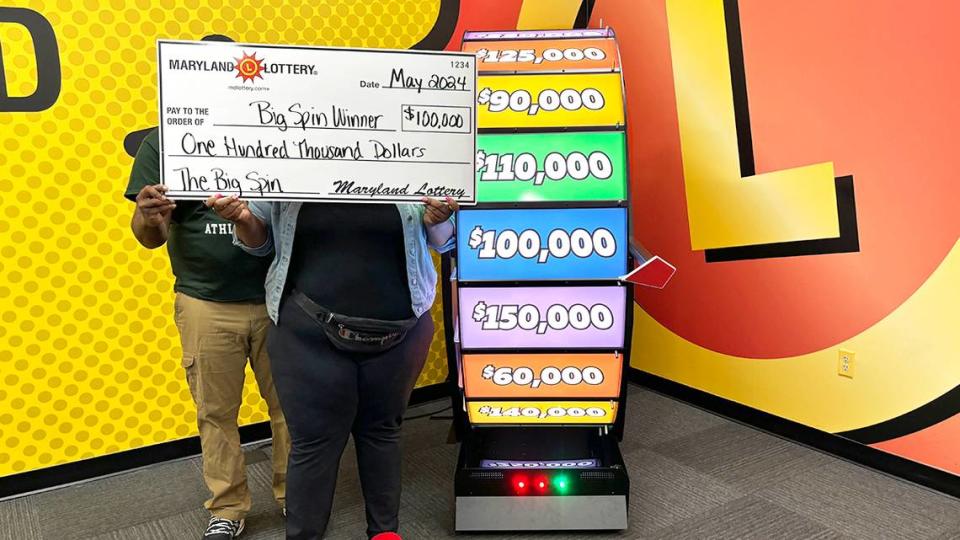 The woman and her fiancé hold a large check after winning $100,000.  Maryland Lottery