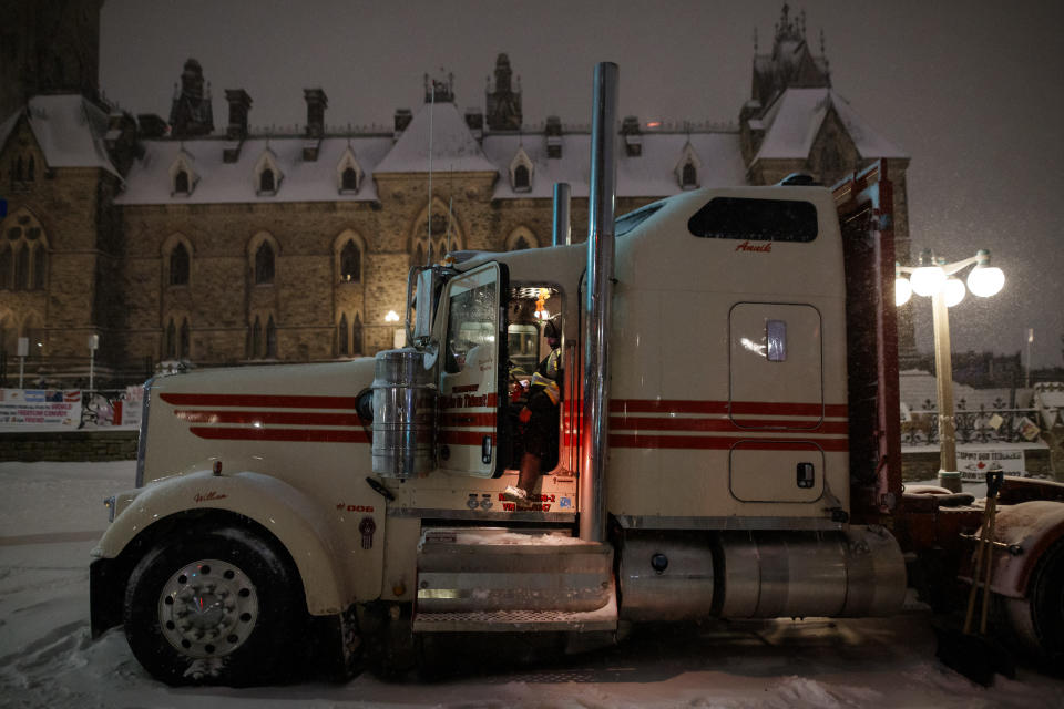 A man sits in a truck as people gather during a protest against COVID-19 measures that has grown into a broader anti-government protest that continues to occupy downtown Ottawa, Ontario, on Thursday, Feb. 17, 2022. (Cole Burston/The Canadian Press via AP)