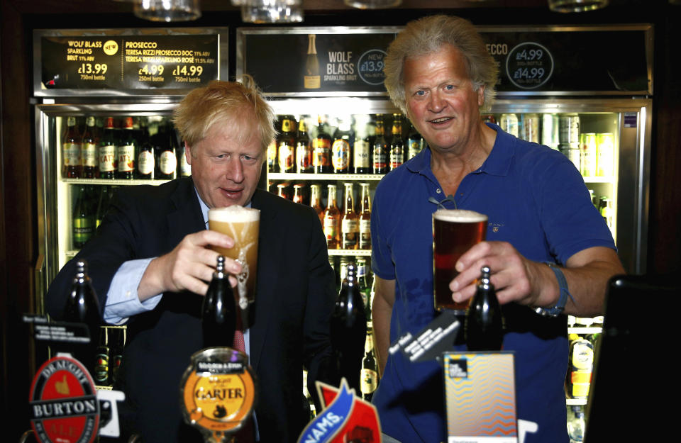 Conservative Party leadership candidate Boris Johnson, left, gestures with Tim Martin, Chairman of JD Wetherspoon, during a visit to Wetherspoons Metropolitan Bar in London, Wednesday July 10, 2019. (Henry Nicholls/Pool Photo via AP)