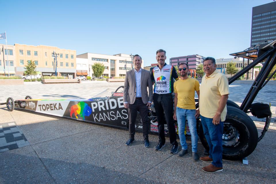 From left, Sean Dixon, president of Visit Topeka, drag racer Travis Shumake, Shawn Zarazua, with Pride Kansas, and Topeka mayor Mike Padilla pose for a photo by Shumake's car at Evergy Plaza Wednesday morning.