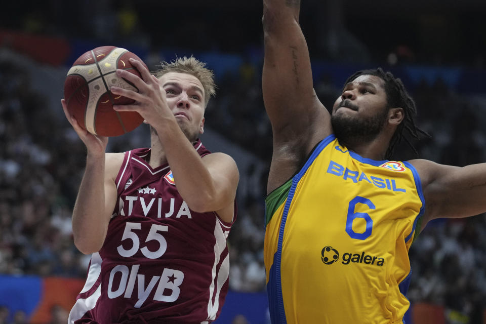 Latvia guard Arturs _agars (55) shoots over Brazil center Cristiano Felicio (6) during the Basketball World Cup second round match between Brazil and Latvia at the Indonesia Arena stadium in Jakarta, Indonesia, Sunday, Sept. 3, 2023. (AP Photo/Tatan Syuflana)