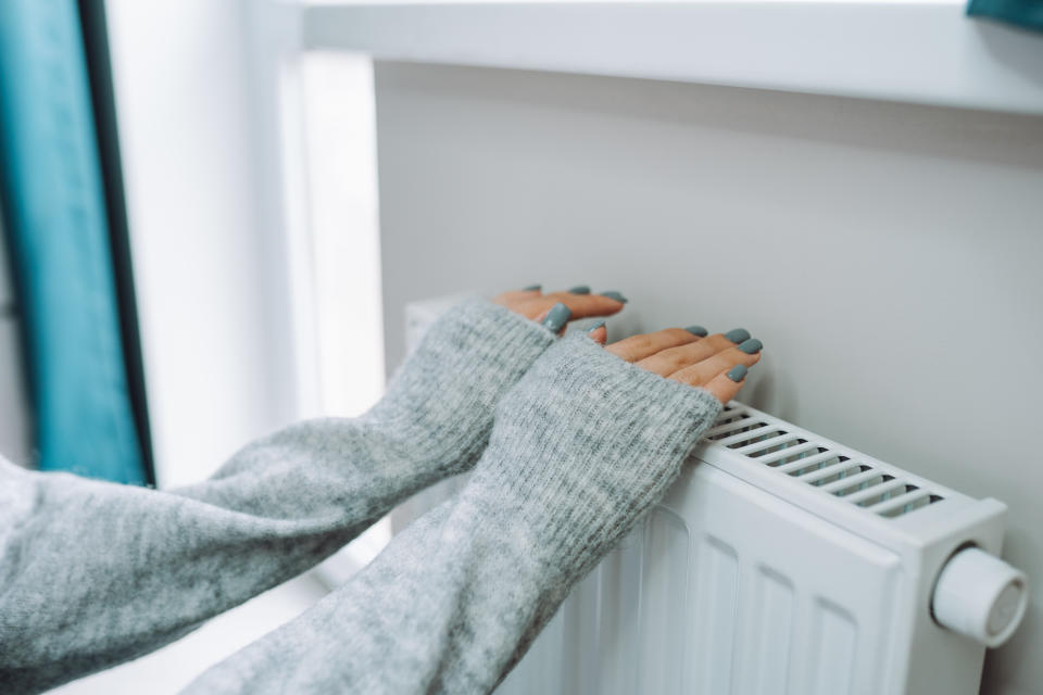 Pair of hands on radiator - Martin Lewis has revealed his best advice for staying warm at home. (Getty Images)