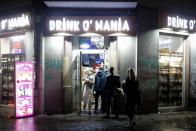 People leave and enter a so called 'Spaeti', a late night shop that sells alcohol and tobacco, amongst other things, near the RAW area, a popular nightlife spot at the district Friedrichshain in Berlin, Germany, Friday, Oct. 23, 2020. (AP Photo/Markus Schreiber)