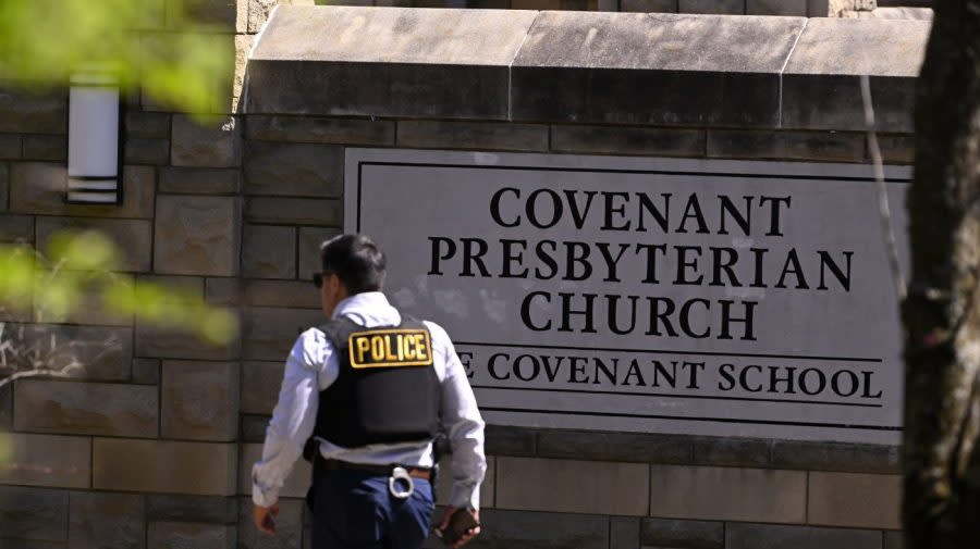 A police officer walks by an entrance to The Covenant School after a shooting in Nashville, Tenn. on Monday, March 27, 2023. (AP Photo/John Amis)