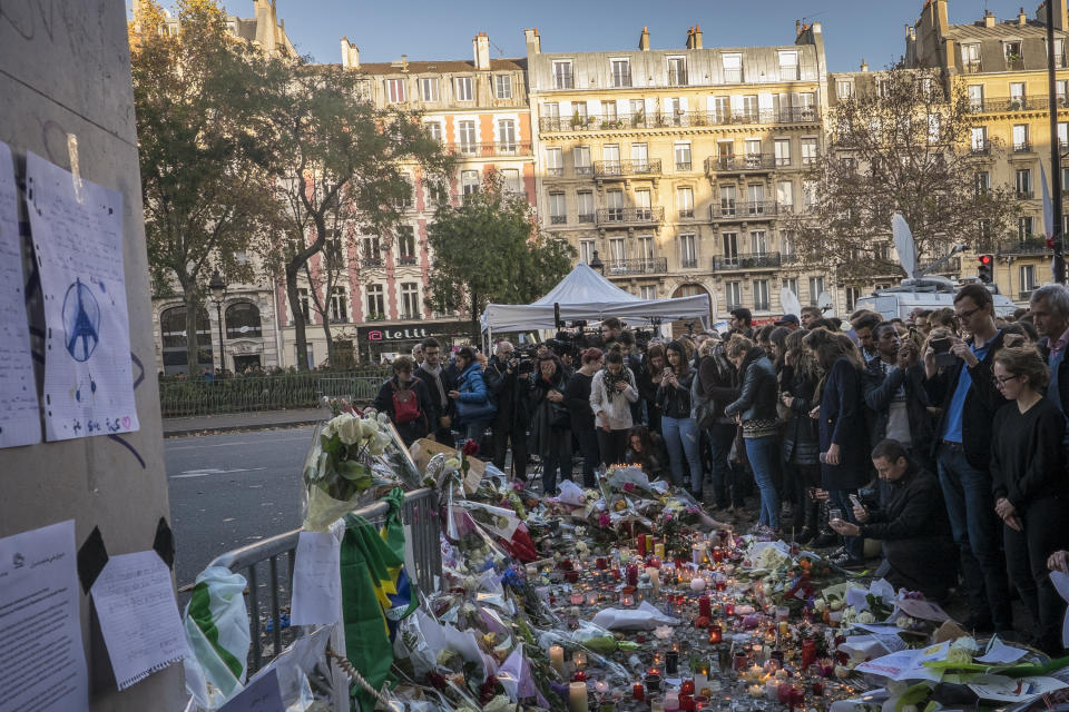 Varias personas hacen un homenaje a las víctimas de los ataques que se produjeron en París, en el exterior de la sala Bataclán. Murieron más de 130 personas. La foto es del 15 de noviembre de 2015, solo dos días después de los atentados. (Olivier Donnars/NurPhoto/Getty)