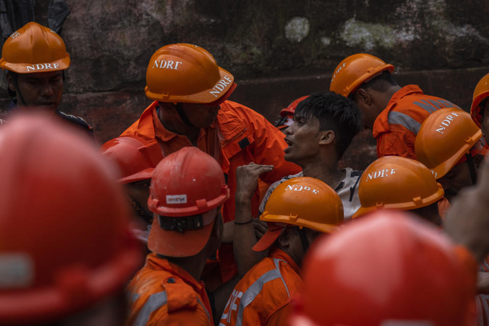 A man is rescued from the debris of a four-story residential building that collapsed in Mumbai, India, Tuesday, June 28, 2022. At least three people died and more were injured after the building collapsed late Monday night. (AP Photo/Rafiq Maqbool)