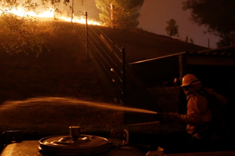 A firefighter hoses a hot spot while battling the Kincade fire in Geyserville, California