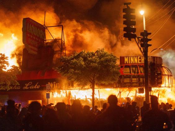 Protesters gather in front of a liquor store in flames near the police building in Minneapolis (AFP via Getty Images)