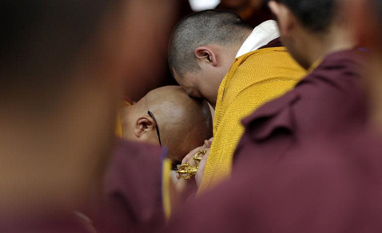 Senior Tibetan Buddhist guru Gyalwang Karmapa (R) consoles a monk during the cremation ceremony of senior Tibetan Buddhist monk Shamar Rinpoche at Shar Minub monastery in Kathmandu on July 31, 2014