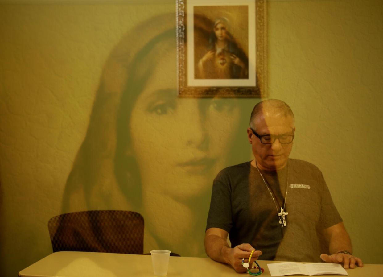 St. Dymphna, the patron saint of mental health, appears in a double-exposure as Ray Martinez recites the rosary.