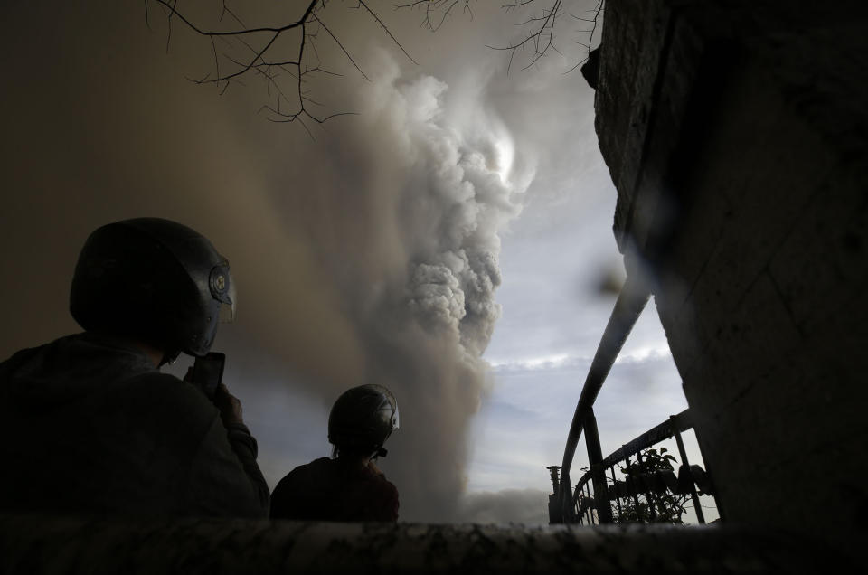 In this Sunday, Jan. 12, 2020, photo, people watch as Taal Volcano erupts, in Tagaytay, Cavite province, outside Manila, Philippines. A tiny volcano near the Philippine capital that draws many tourists for its picturesque setting in a lake belched steam, ash and rocks in a huge plume Sunday, prompting thousands of residents to flee and officials to temporarily suspend flights. (AP Photo/Aaron Favila)