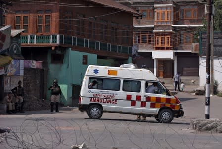 An ambulance is pictured as Indian policemen stand guard in a street during restrictions in Srinagar