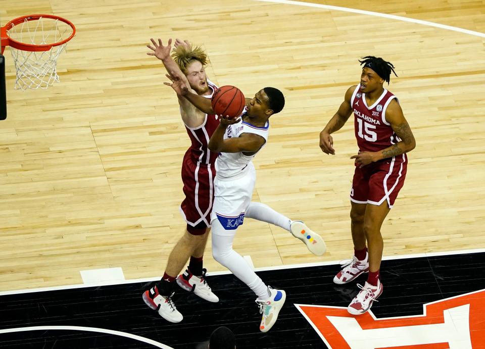 Bryce Thompson of Kansas goes up between former Oklahoma players Brady Manek, left, and Alondes Williams, right, in March of last season during a Big 12 Tournament game.