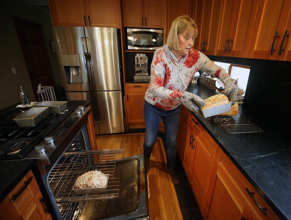 Peggy Koivu removes four freshly baked loaves of honey oat bread from the oven in her Indianola home on Friday, Jan. 26, 2024. Koivu has made 573 loaves of bread for the Community Loaves program since December 2020.