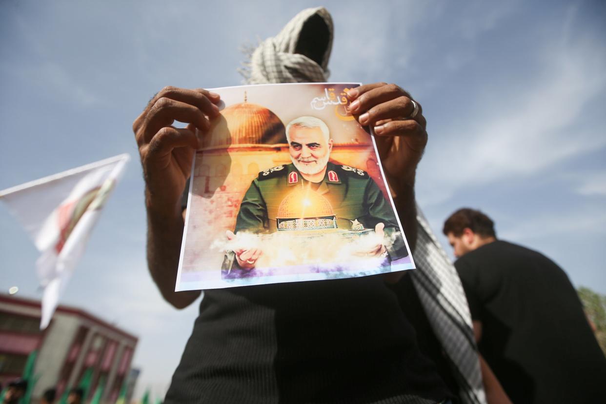 <p>A militia member shows a picture of Qassem Soleimani, whose death has inflamed tensions</p> (Reuters)