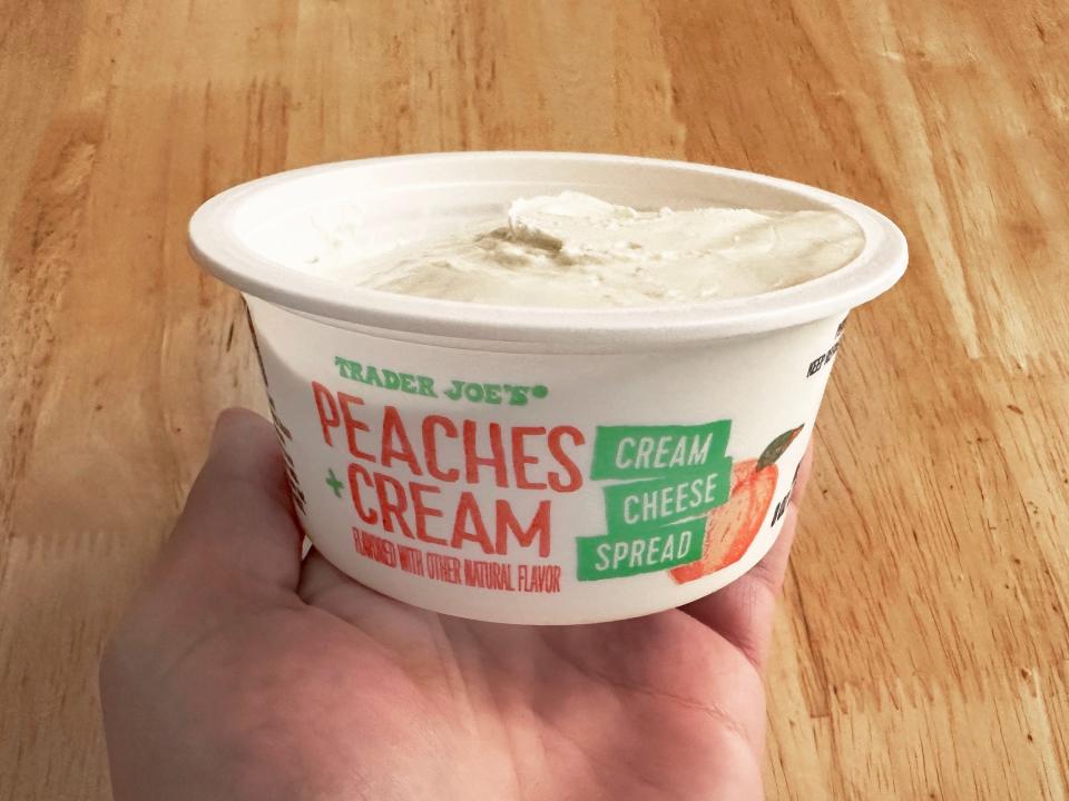 A hand holds a white container with "Peaches and Cream" in orange text, as well as green graphics, on the package