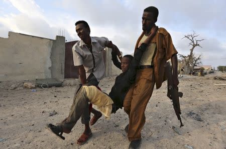 Residents evacuate an injured boy after Islamist group al Shabaab attacked Maka Al-Mukarama hotel in Mogadishu, March 27, 2015. REUTERS/Feisal Omar