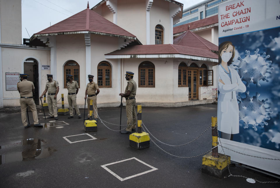 Policemen stand guard next to markings made to ensure physical distancing outside the Kochi Special Economic Zone during a nation wide strike by various trade unions in Kochi, Kerala state, India, Thursday, Nov. 26, 2020. India has more than 9 million cases of coronavirus, second behind the United States. (AP Photo/R S Iyer)