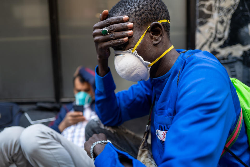 Sylla, wearing a white construction mask, puts his hand on his forehead.