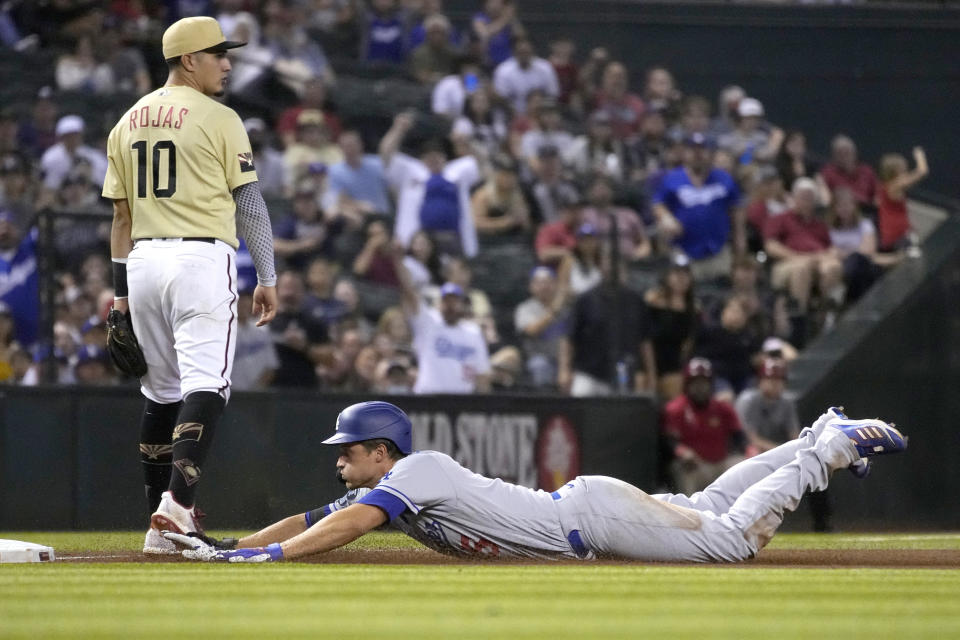 Los Angeles Dodgers shortstop Corey Seager dives into third base in front of Arizona Diamondbacks third baseman Josh Rojas (10)after hitting a triple in the seventh inning during a baseball game, Friday, Sept. 24, 2021, in Phoenix. (AP Photo/Rick Scuteri)