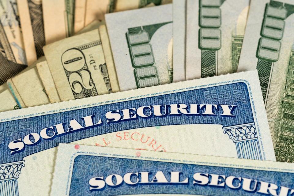 Two Social Security cards on top of a pile of cash.