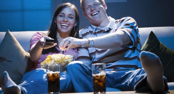 ADWDGT Couple sitting on sofa watching television with bowl of popcorn smiling  date; laughing; movie; tv; Adults; Beverages; Bo