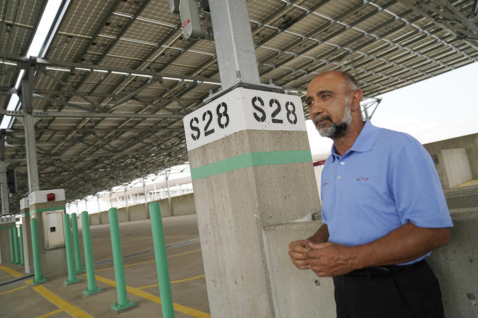 Ahmad Kian, president of Apadana Solar Technologies, poses Aug. 20, 2021 beneath a "community solar" garden his company designed for installation atop Ramp A, a downtown parking garage in Minneapolis. The installation consists of 3,760 panels on a parking deck overlooking the Twins' baseball stadium. Aug. 20, 2021, in Minneapolis. (AP Photo/Jim Mone)