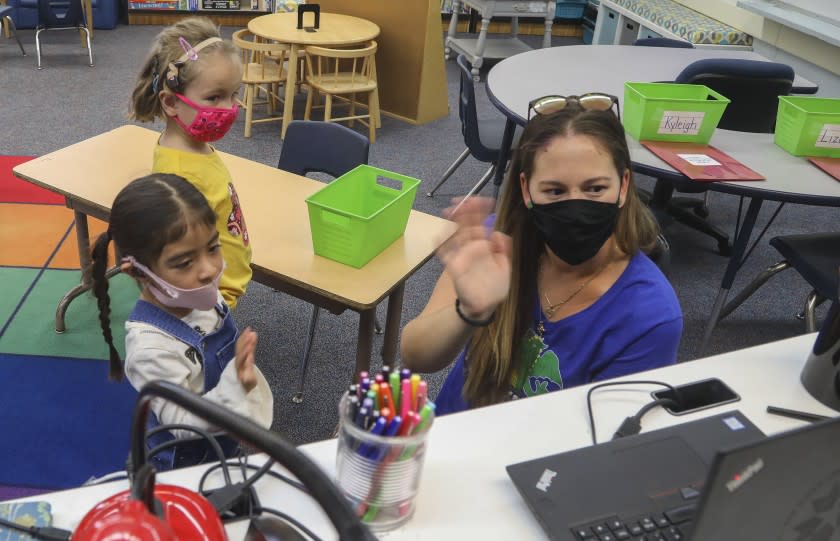 SAN DIEGO, CA - OCTOBER 13: Pre-K teacher Amanda Templeton (right) waves hello to online learners with Lizeth Hernandez (left) and Kyleigh Maunaury-Young (middle) on the first day of in person learning at Lafayette Elementary School on Tuesday, Oct. 13, 2020 in San Diego, CA. (Eduardo Contreras / The San Diego Union-Tribune)