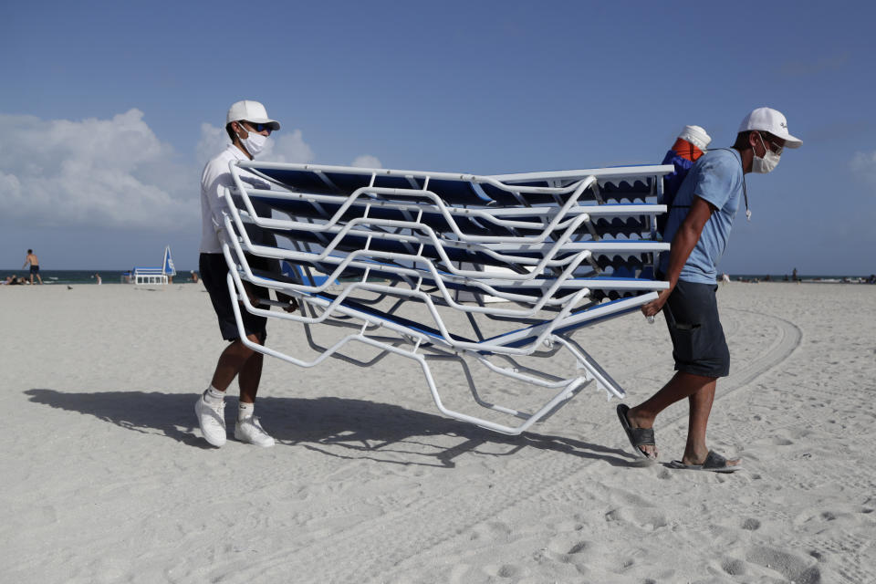 Workers remove chairs from the beach in preparation for Hurricane Isaias, Friday, July 31, 2020, in Miami Beach, Fla. Forecasters declared a hurricane warning for parts of the Florida coast Friday as Hurricane Isaias drenched the Bahamas on track for the U.S. East Coast. (AP Photo/Lynne Sladky)