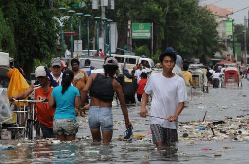 Residents wade through a flooded street filled with rubbish in the town of Navotas, in suburban Manila on August 1, 2012. Rescuers deployed rubber boats while doctors fanned across cramped evacuation centres in the Philippines as the death toll from five days of flooding reached 23 on Thursday, officials said