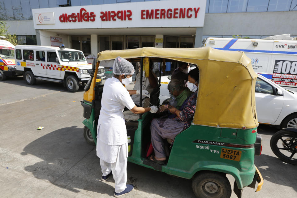 A COVID-19 patient attended by a health worker inside a vehicle at a dedicated COVID-19 government hospital in Ahmedabad, India, Thursday, April 22, 2021. A fire killed 13 COVID-19 patients in a hospital in western India early Friday as an extreme surge in coronavirus infections leaves the nation short of medical care and oxygen. India reported another global record in daily infections for a second straight day Friday, adding 332,730 new cases. The surge already has driven its fragile health systems to the breaking point with understaffed hospitals overflowing with patients and critically short of supplies. (AP Photo/Ajit Solanki)