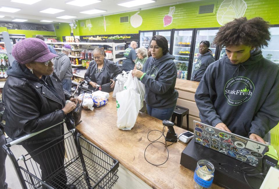 Cashiers Shania Mays and Tray Campbell check out Rentzetta Barnes the first shopper to check out at the new Stark Fresh grocery store in Alliance.