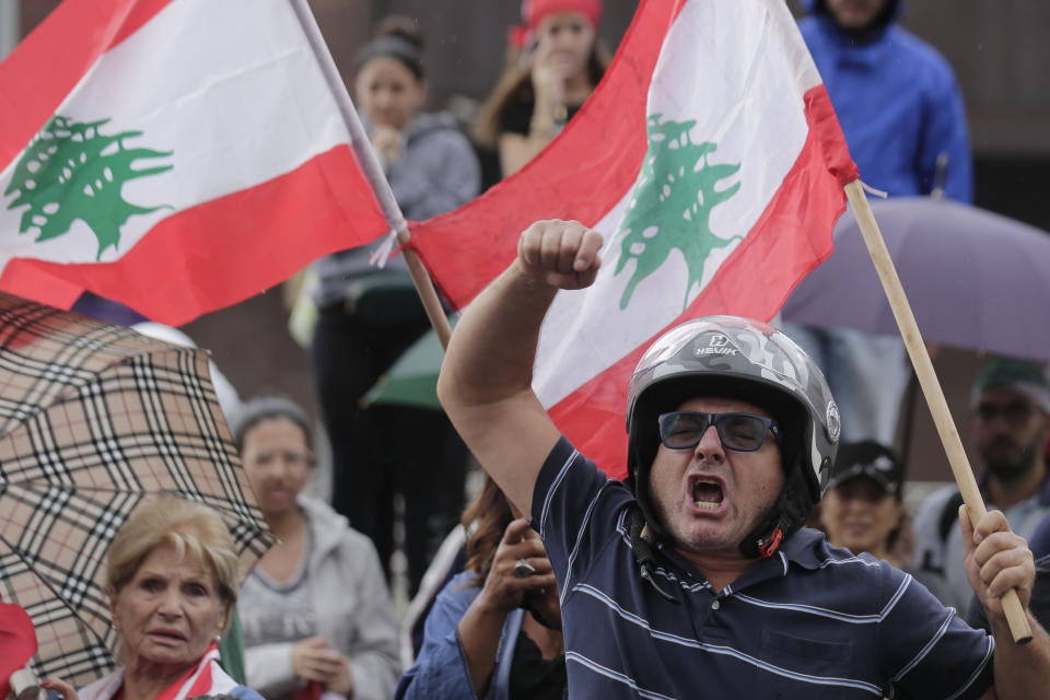 Anti-government protesters shout slogans against Lebanon's President Michel Aoun as they listen on a speaker while he addressees the nation during a protest in the town of Jal el-Dib north of Beirut, Lebanon, Thursday, Oct. 24, 2019. Aoun has told tens of thousands of protesters that an economic reform package put forth by the country's prime minister will be the "first step" toward saving Lebanon from economic collapse. (AP Photo/Hassan Ammar)