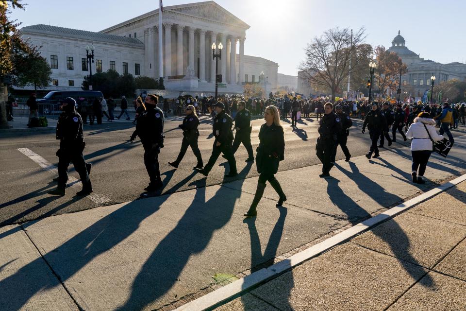 Police officers walk along the road where abortion rights advocates and anti-abortion protesters demonstrate in front of the U.S. Supreme Court, Wednesday, Dec. 1, 2021, in Washington, as the court hears arguments in a case from Mississippi, where a 2018 law would ban abortions after 15 weeks of pregnancy, well before viability. (AP Photo/Andrew Harnik)